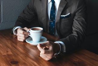 man holding cup filled with coffee on table by Andrew Neel courtesy of Unsplash.
