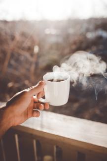 person holding white ceramic cup with hot coffee by Clay Banks courtesy of Unsplash.