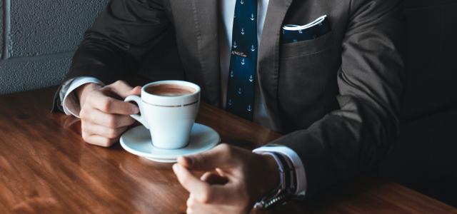 man holding cup filled with coffee on table by Andrew Neel courtesy of Unsplash.