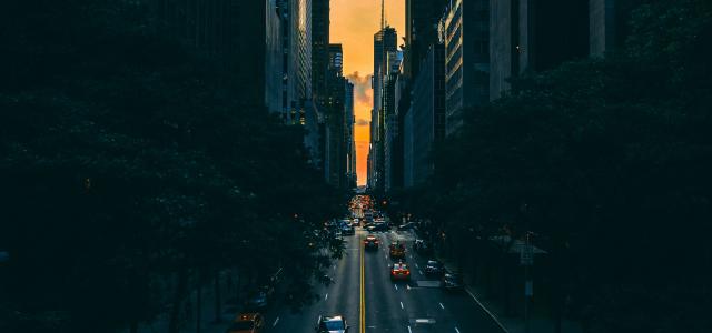 low light photography of vehicle crossing road between high-rise buildings by Malte Schmidt courtesy of Unsplash.